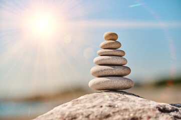 Balanced stone arrangement on a rocky beach under a bright sun