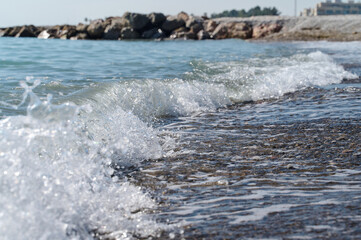 Waves gently lap against the rocky shore on a sunny day by the sea coast