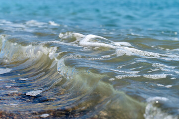 Waves gently rolling onto a sandy beach under bright blue skies during a sunny day