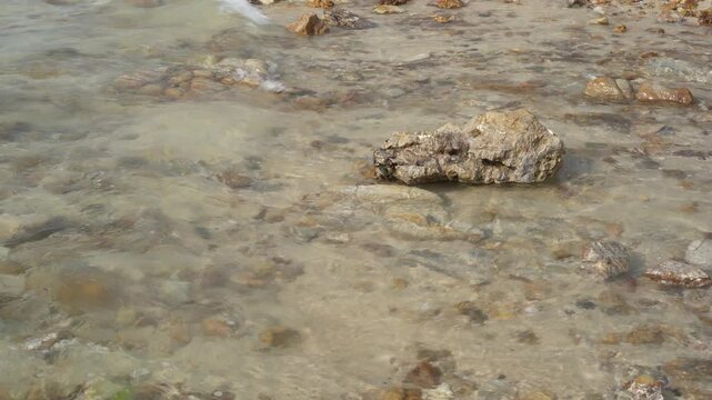 closeup sea sand beach with rocks stones on coast or island with nature little waves for summer holiday travel and daylight seascape landscape background at Sai Kaew Beach Thailand CPL with wave sound
