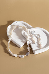 Necklace of various natural baroque pearl beads on beige background. Necklace and earrings