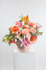 Vibrant floral arrangement for Valentine's Day and International Women's Day with pink roses, orange ranunculus, and tropical lilies