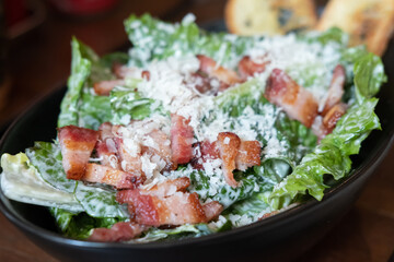 Salad with sliced bacon served in a bowl, on the table