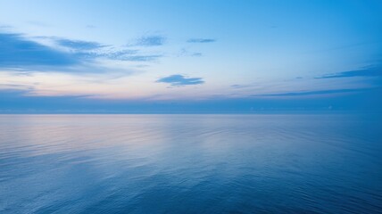 Obraz premium A serene view of the calm ocean at dawn, showcasing beautiful blue hues and a gentle, peaceful atmosphere.