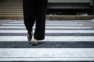 Person crossing a city street using a zebra crossing, emphasizing urban lifestyle and pedestrian...