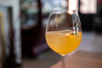 A glass of citrus sangria, featuring a vibrant orange hue with ice and a slice of fruit garnish