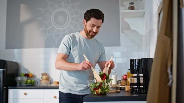 Carefree guy mixing salad home kitchen closeup. Positive man cooking breakfast
