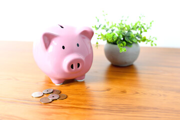 机に置かれた豚の貯金箱と硬貨のイメージ
