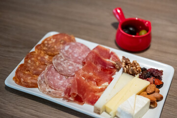 Cold cuts platter, variety of sliced meat and cheese with olives and nuts