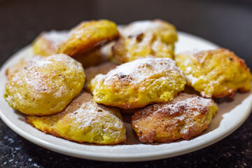 Bright orange pumpkin cookies baked in the oven, sprinkled with powdered sugar, on a white plate