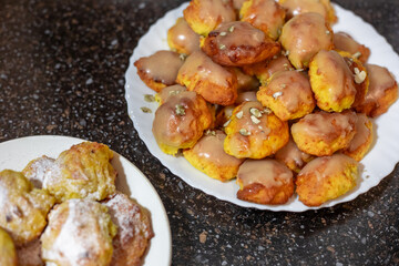 Bright orange pumpkin cookies baked in the oven, covered with icing, on a white plate