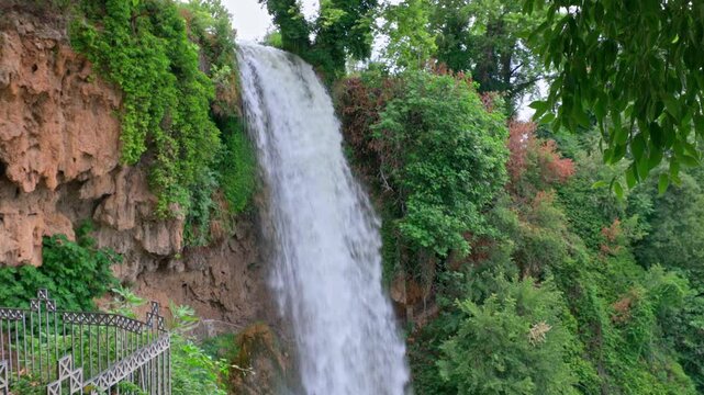 Waterfall cascading over rocky cliff surrounded by lush green vegetation in Edessa, Greece.