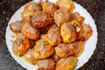 Bright orange pumpkin cookies baked in the oven, covered with icing, on a white plate