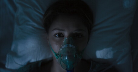 Female patient wearing oxygen mask looking directly at camera.