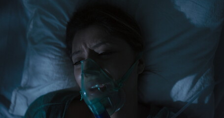 Young girl patient in a hospital room lying in intensive care wearing an oxygen mask.