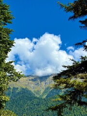 Obraz premium Blue sky and clouds heart shaped over mountains. Сoncept world wildlife day. Nature postcard