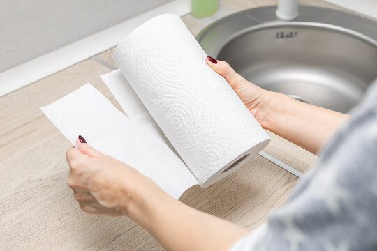 woman's hand ripping off paper towel in kitchen. housewife uses paper towel. roll of paper towel in the kitchen. kitchen cleaning