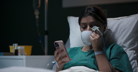 Patient reclining in hospital room, wearing nasal oxygen tube, having a video conversation.