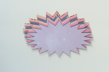 isolated staggered pile of machine-cut paper shapes with starburst effect on blank paper
