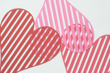 Obraz premium striped heart shapes machine-cut from pink and red crafting paper and arranged on blank paper