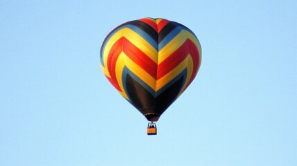 Fototapeta premium A colorful hot air balloon rising into a clear blue sky.