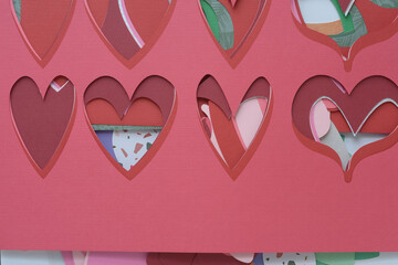 stencil with heart pattern machine-cut from a variety of pink and red crafting papers and arranged...
