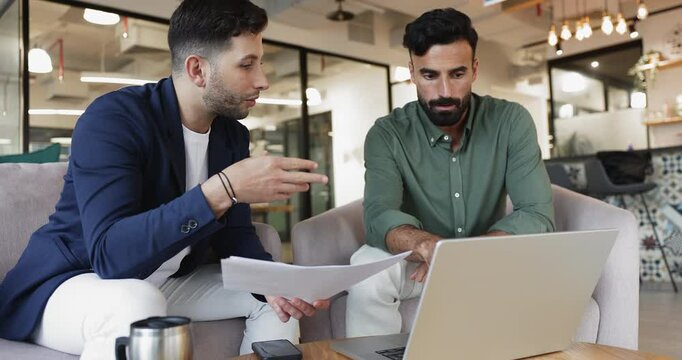 Colleagues collaborate in office using printed documents and laptop, explain point, learning data, discussing report and joint task, reviewing presentation or proposal. Brainstorming, problem-solving