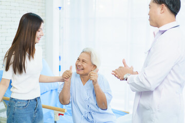 Obraz premium Asian woman helps her recovering mother with light exercises in the hospital.