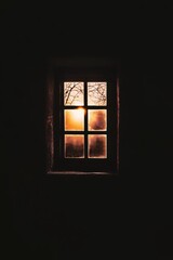 Fototapeta premium Window to Warmth: A square window glows warmly against a dark backdrop, offering a glimpse of a vibrant outdoor scene. The simplicity evokes introspection.