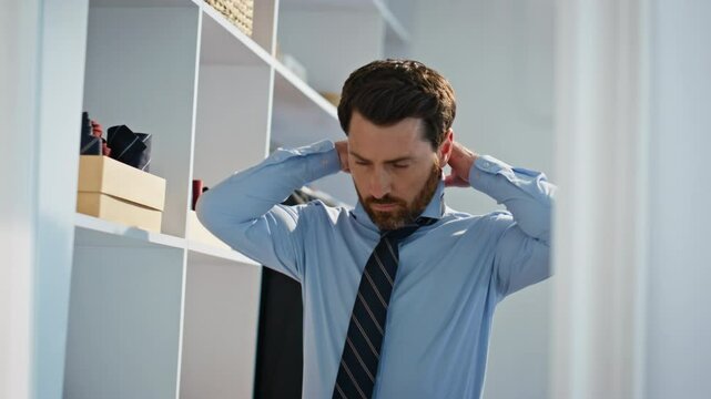 Serious businessman wearing tie at wardrobe closeup. Director preparing for work