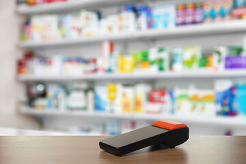 Payment terminal on wooden counter in drugstore. Space for text