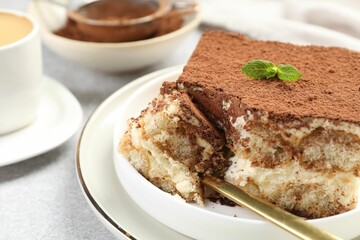 Delicious tiramisu with mint on light table, closeup