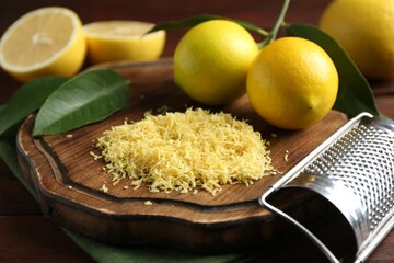Lemon zest, grater and fresh fruits on wooden table, closeup