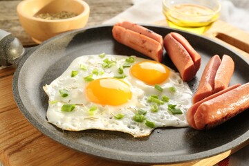 Tasty fried eggs with cut sausages served on table, closeup