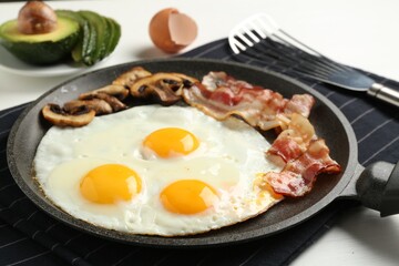 Tasty fried eggs with bacon and mushrooms served on white table, closeup