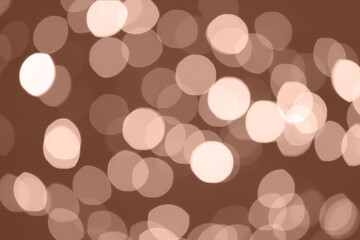 Blurred bokeh lights toned in mocha mousse shade. Trendy color of 2025 year