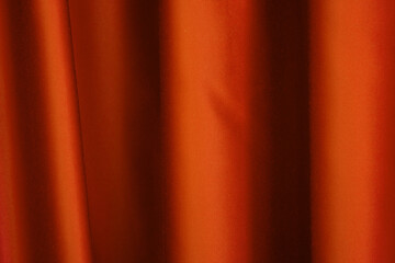 Vibrant orange curtain drapes elegantly in soft light during an indoor gathering