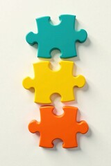 Obraz premium Three vibrant puzzle pieces vertically aligned, representing unity and collaboration in problem-solving