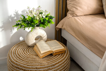Cozy bedroom corner with a plant and an open book on a round table