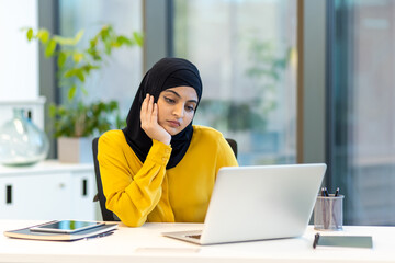 Bored upset woman working inside office with notebook, businesswoman in hijab, Arab woman pensive,...