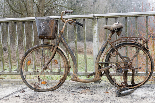 Ein altes, verlassenes, rostiges Fahrrad, das an einem Gel&auml;nder geparkt ist. Das Fahrrad lag einige Jahre im Fluss.