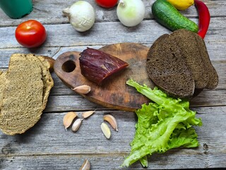 Dried meat on a cutting board surrounded by vegetables.
