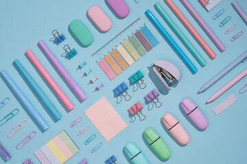 Stationery background with pastel-colored office supplies neatly arranged on a light blue background. Workplace organization. Back to school concept.