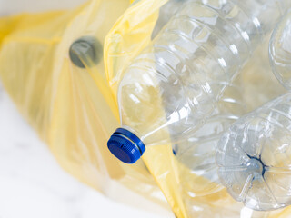 Plastic bottles inside yellow trash bag awaiting recycling