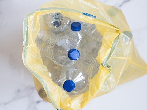 Plastic bottles inside yellow trash bag awaiting recycling