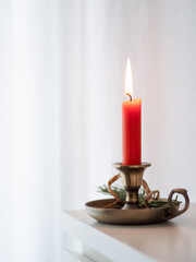 Red candle burning on a brass candlestick with decoration