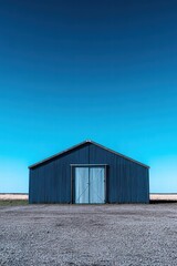 Obraz premium Blue Barn Against a Clear Sky in a Rural Landscape