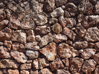 Fragment of a wall made of natural stone in brown shades