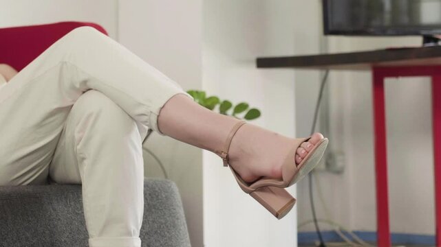Woman Relaxing on Couch in Office: High Heels and Modern Interior