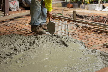 Worker pouring wet concrete over metal reinforcement on construction site